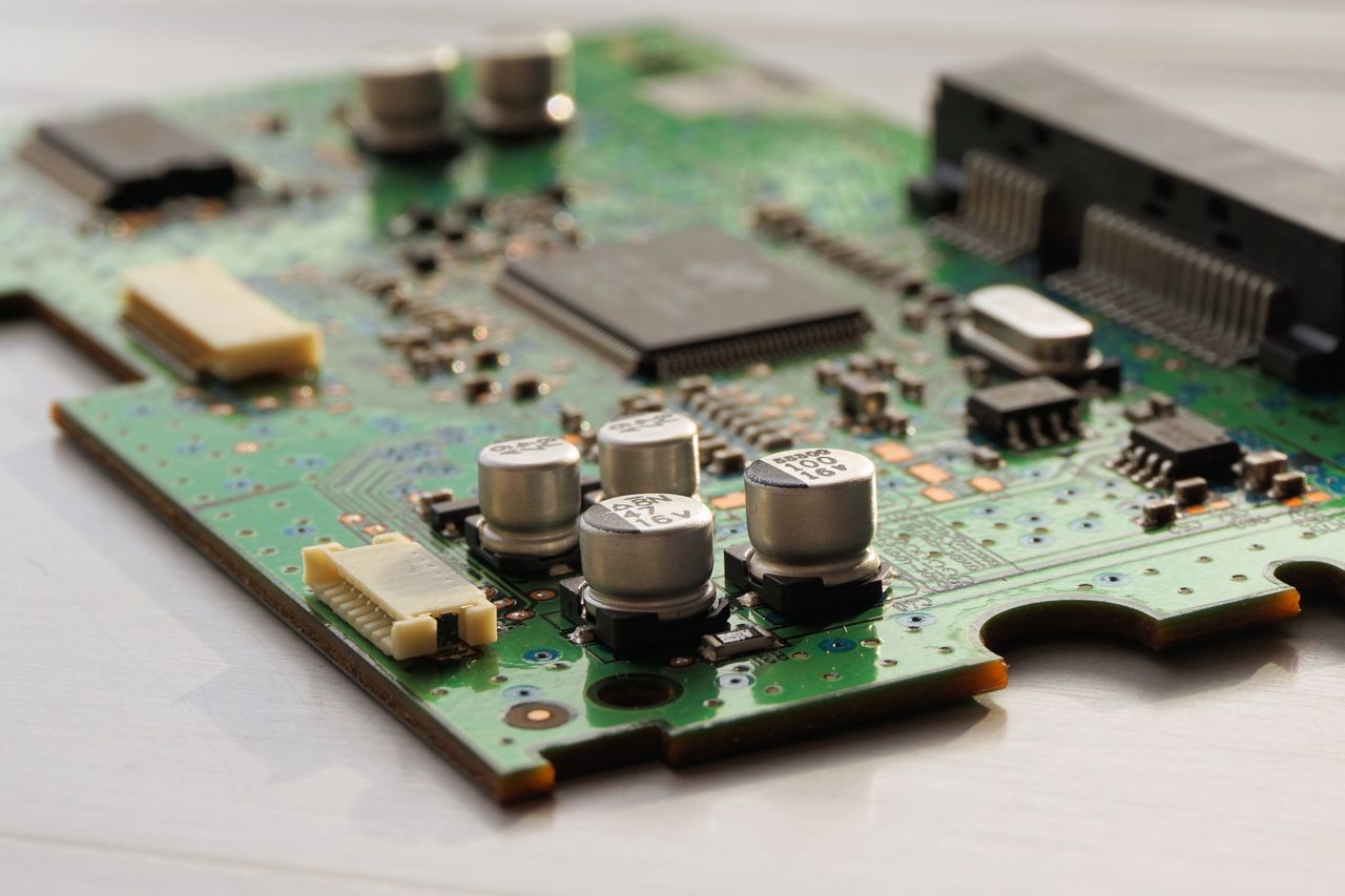 Offerings Detailed view of a green circuit board featuring capacitors and microchips.